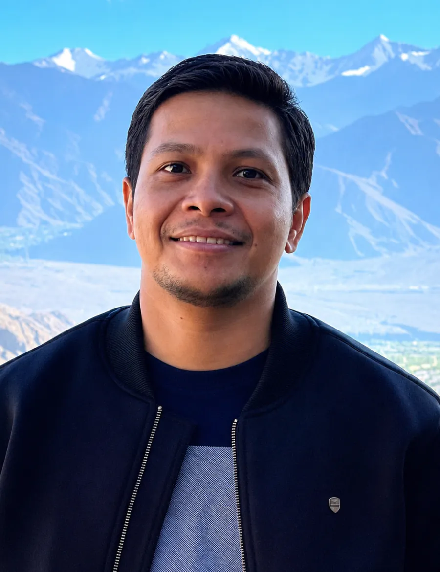Portrait outdoors, snow-covered peaks on the horizon behind.